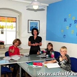 3 Schüler sitzen am Tisch beim Nachhilfeunterricht mit der Nachhilfelehrkraft